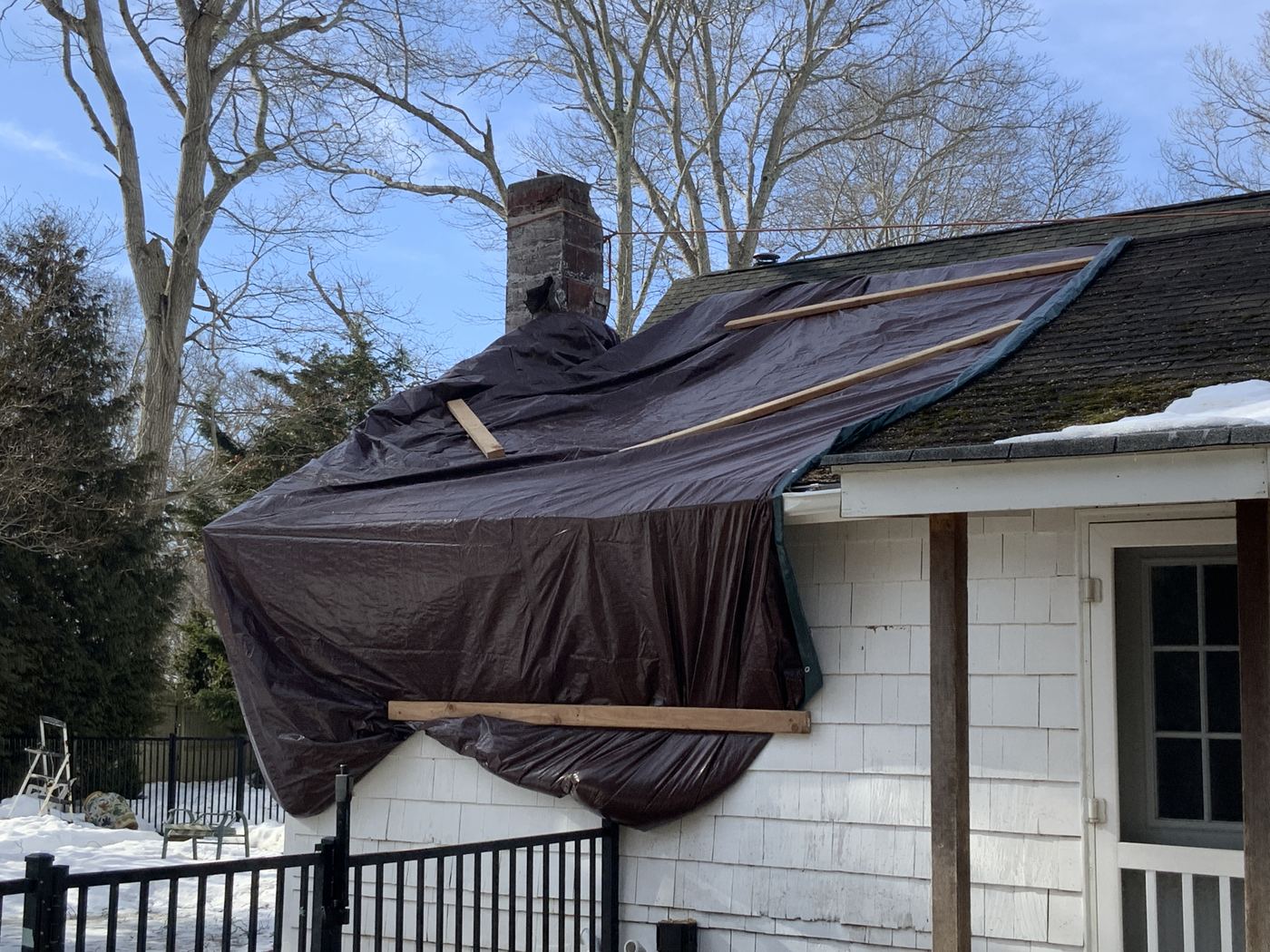 Emergency tarp over storm-damaged roof and chimney